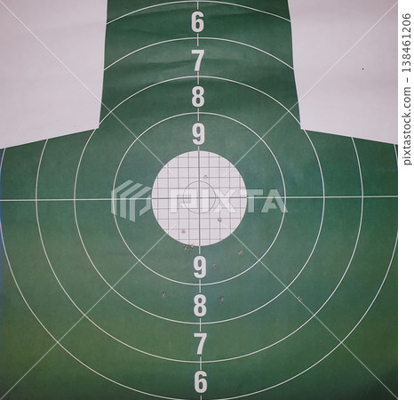 Green paper shooting target with bullet holes in the bullseye. Concept of precision, marksmanship, firearms training, hitting the goal, success, and professional shooting practice. 138461206
