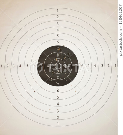 Close-up of white paper target with multiple bullet holes concentrated near the central bullseye rings. target. Close-up of white paper target with multiple bullet holes concentrated near the central bullseye rings. target. 138461207