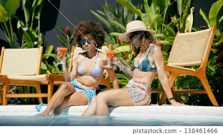 Women enjoying cocktails by tropical pool on vacation 138461466