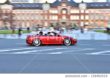 A red open-top car drives in front of the Marunouchi South Exit of Tokyo Station. A red open-top car drives in front of the Marunouchi South Exit of Tokyo Station. 138462019
