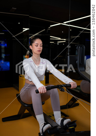 Young woman training on indoor rowing machine at gym Young woman training on indoor rowing machine at gym 138462842