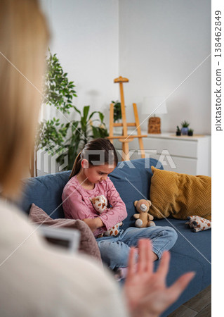 Unhappy girl receiving child therapy from psychologist 138462849