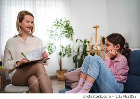 Female psychologist providing therapy to a young girl on a sofa Female psychologist providing therapy to a young girl on a sofa 138462852