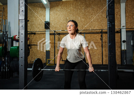 Woman doing weightlifting exercise with barbell in gym Woman doing weightlifting exercise with barbell in gym 138462867