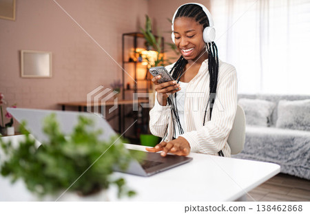 Young african american woman enjoying music and working from home Young african american woman enjoying music and working from home 138462868