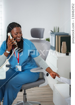 Medical professional talking on telephone in office Medical professional talking on telephone in office 138462952