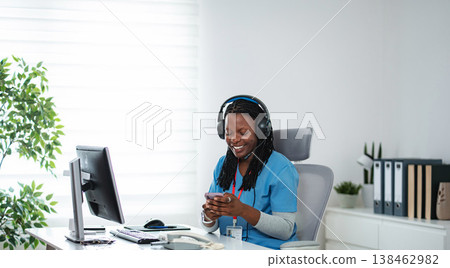 Medical professional using smartphone and headset at office desk Medical professional using smartphone and headset at office desk 138462982
