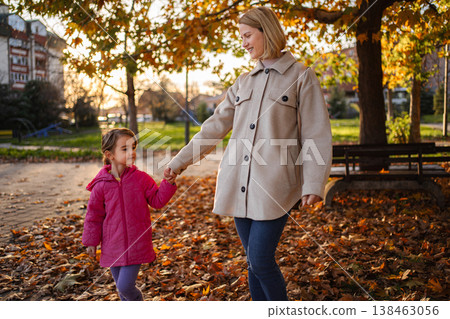 Mother and daughter holding hands walking in autumn park Mother and daughter holding hands walking in autumn park 138463056