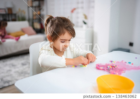 Little girl playing with colorful beads making jewelry at home 138463062