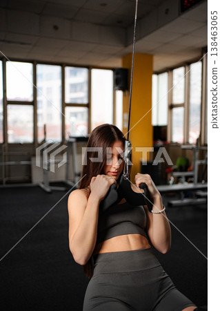 Young adult woman exercising doing triceps pushdown at gym 138463065