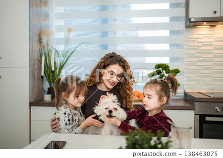 Mother and daughters bonding with pet dog in kitchen 138463075