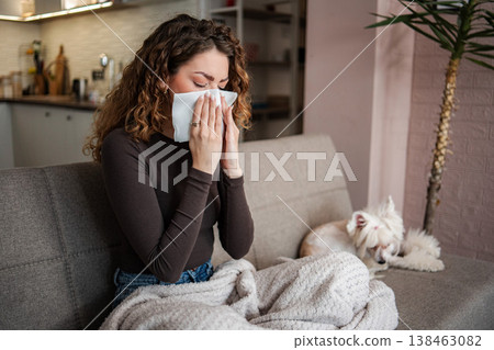 Young woman blowing nose having allergy symptoms with pet dog 138463082