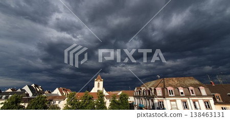 Phone photo of dramatic dark clouds over the rooftops of Strasbourg. Moody urban sky scene showing storm weather, architecture, and tense atmosphere. Phone photo of dramatic dark clouds over the rooftops of Strasbourg. Moody urban sky scene showing storm weather, architecture, and tense atmosphere. 138463131
