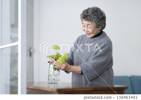 Senior woman decorating her room with flowers Senior woman decorating her room with flowers 138463481