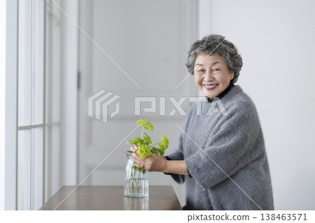Senior woman decorating her room with flowers, portrait looking at camera and smiling Senior woman decorating her room with flowers, portrait looking at camera and smiling 138463571