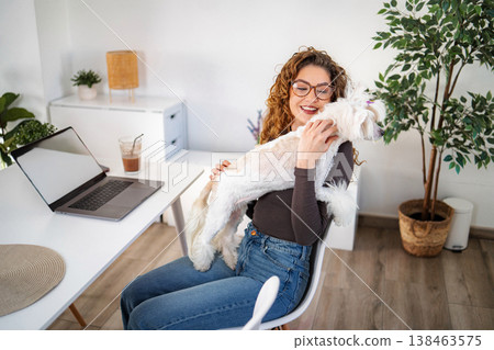 Woman embracing dog working from home with laptop 138463575