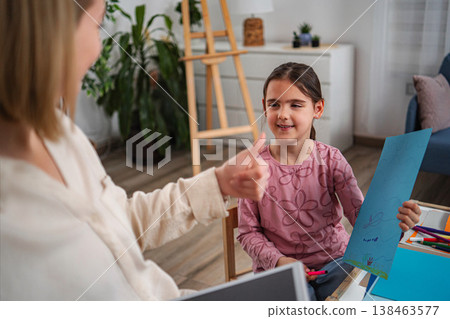 Child smiling showing artwork while therapist gives a thumbs up Child smiling showing artwork while therapist gives a thumbs up 138463577