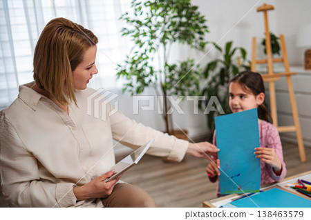 Woman giving drawing to cute young girl for art therapy 138463579