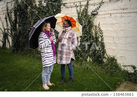 Two diverse friends communicating outdoors on rainy autumn day Two diverse friends communicating outdoors on rainy autumn day 138463661