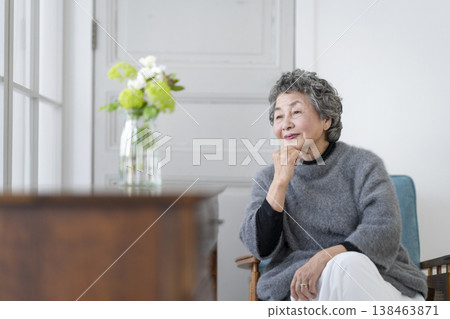 一位老婦人手托下巴，面帶微笑。 138463871
