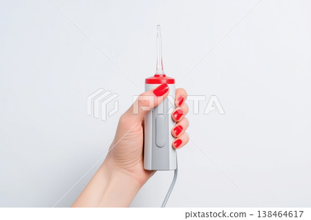 Woman's hand with red nails holding a portable water flosser Woman's hand with red nails holding a portable water flosser 138464617