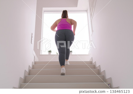 Overweight Woman Climbing Stairs Indoors 138465123
