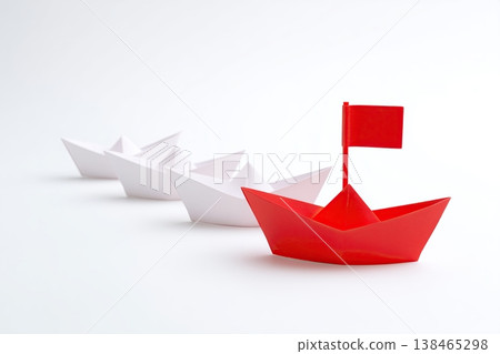 Red paper boat leading a fleet of white origami boats, symbolizing leadership and direction in a business or strategic context. Red paper boat leading a fleet of white origami boats, symbolizing leadership and direction in a business or strategic context. 138465298