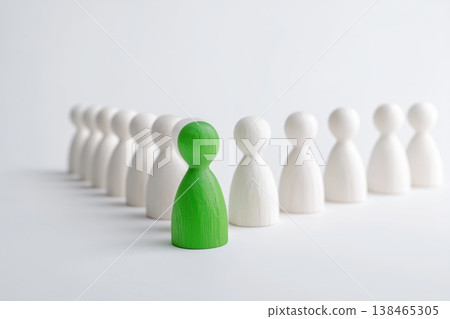 Green wooden figure stands out from a group of white figures, suggesting leadership or individuality concept. Green wooden figure stands out from a group of white figures, suggesting leadership or individuality concept. 138465305