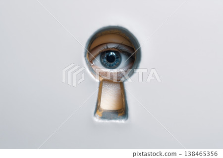 An intriguing blue eye peers through a vintage keyhole, symbolizing observation, security, and curiosity in a white door. An intriguing blue eye peers through a vintage keyhole, symbolizing observation, security, and curiosity in a white door. 138465356