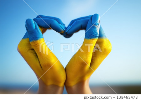 Hands painted in Ukrainian colors forming a heart shape against bright blue sky, representing peace, solidarity, and support. Hands painted in Ukrainian colors forming a heart shape against bright blue sky, representing peace, solidarity, and support. 138465478