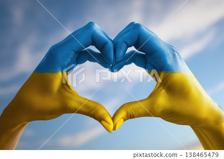Hands painted in Ukrainian flag colors forming a heart against a blue sky evoke themes of support and solidarity. Hands painted in Ukrainian flag colors forming a heart against a blue sky evoke themes of support and solidarity. 138465479