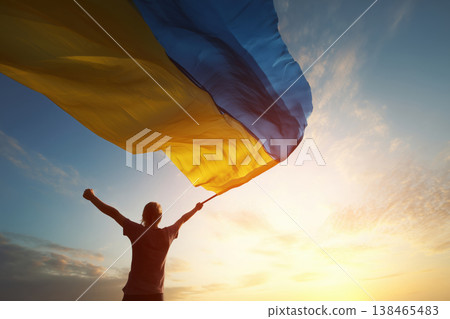 Person holds Ukrainian flag with pride against a sky during sunset showing patriotism Person holds Ukrainian flag with pride against a sky during sunset showing patriotism 138465483