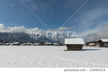 Snowy barn with footprints leading across winter field toward alpine mountain in Bavaria Snowy barn with footprints leading across winter field toward alpine mountain in Bavaria 138465818