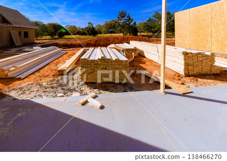Lumber beams is stacked at construction site where building activities take place under framework Lumber beams is stacked at construction site where building activities take place under framework 138466270