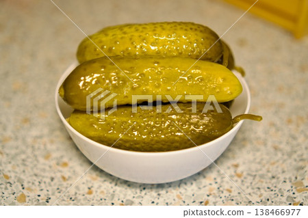 Crunchy pickled cucumbers in a white bowl on a kitchen table, traditional homemade appetizer. 138466977