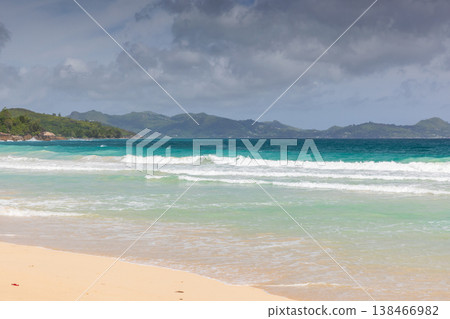 Turquoise ocean waves gently roll onto a wide beach 138466982