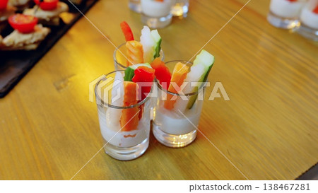 Vibrant vegetable stickscarrots, cucumbers, bell peppersnestled beside creamy dip, arranged in small glasses on rustic wooden surface, offering fresh, nutritious snacking option Vibrant vegetable stickscarrots, cucumbers, bell peppersnestled beside creamy dip, arranged in small glasses on rustic wooden surface, offering fresh, nutritious snacking option 138467281