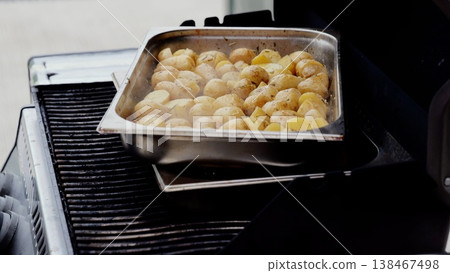 Rosemary infused roasted potatoes sizzling on metal grill tray, radiating golden brown color and savory herb aroma during backyard barbecue gathering Rosemary infused roasted potatoes sizzling on metal grill tray, radiating golden brown color and savory herb aroma during backyard barbecue gathering 138467498