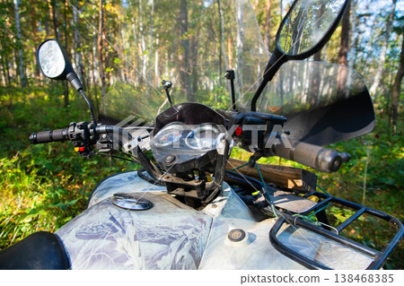All Terrain Vehicle outside. ATV Quadbike parked in a dense forest during a clear day exploring nature's beauty and adventure All Terrain Vehicle outside. ATV Quadbike parked in a dense forest during a clear day exploring nature's beauty and adventure 138468385