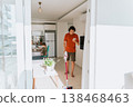 Man wireless vacuum cleaner headphones looking smartphone while spring-cleaning the house. Caucasian male in wireless earphones checking message in cellphone vacuum cleaning light cozy apartment 138468463