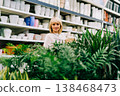 Gardening, planting and shopping concept. Beautiful mature adult woman choosing houseplants and pots in greenhouse or garden centre. Senior buying flowers plants at market store in mall 138468473