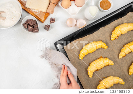 Raw croissants on baking tray with baking ingredients, top view. Raw croissants on baking tray with baking ingredients, top view. 138468550