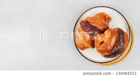 Chocolate croissants on plate in top view on light background with copy space 138468551