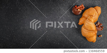 Croissants with chocolate spread and hazelnuts on dark background with copy space 138468559