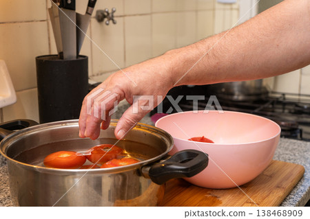 Removing tomato from pot into bowl Removing tomato from pot into bowl 138468909
