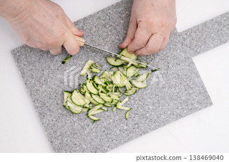 A woman's hands cutting a cucumber on a gray board 138469040