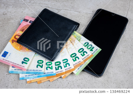 Paper money in black partmone and smartphone on the table. Cash euro bills in leather wallet with mobile phone for commerce concept. Paper money in black partmone and smartphone on the table. Cash euro bills in leather wallet with mobile phone for commerce concept. 138469224