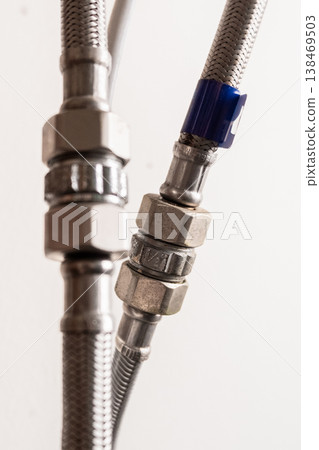 Close-up of a metal water hose connected to a water heater. The hose features a threaded connector and is made of durable material, suitable for plumbing applications. Close-up of a metal water hose connected to a water heater. The hose features a threaded connector and is made of durable material, suitable for plumbing applications. 138469503
