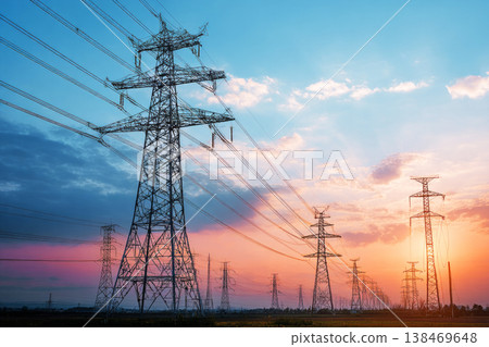 Power transmission lines stand tall along a wide road, connecting areas as clouds drift overhead. This scene shows the infrastructure for transporting electricity through the landscape Power transmission lines stand tall along a wide road, connecting areas as clouds drift overhead. This scene shows the infrastructure for transporting electricity through the landscape 138469648