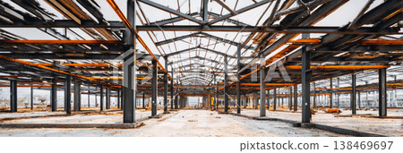 Construction work is ongoing at a site with a visible steel framework and concrete floors. Workers are busy assembling the structure during daylight hours Construction work is ongoing at a site with a visible steel framework and concrete floors. Workers are busy assembling the structure during daylight hours 138469697